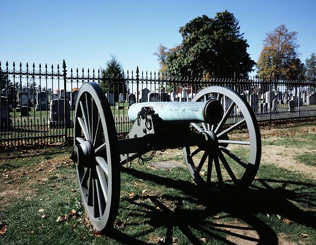 Civil War cannon silhouetted against the historic iron fence at Gettysburg National Cemetery Pennsylvania